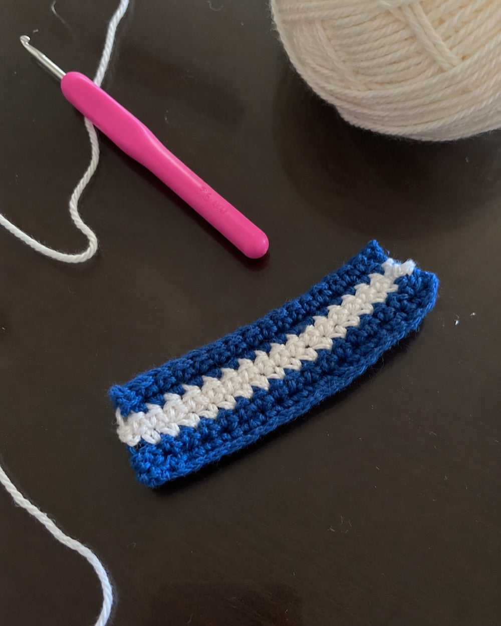 A crochet piece in progress with hook and yarn